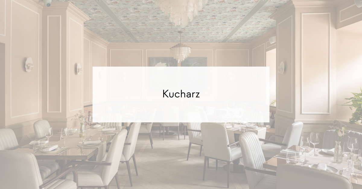 Elegant restaurant dining room with linen tables, glassware, and cream chairs; overlay reads 'Kucharz'.
